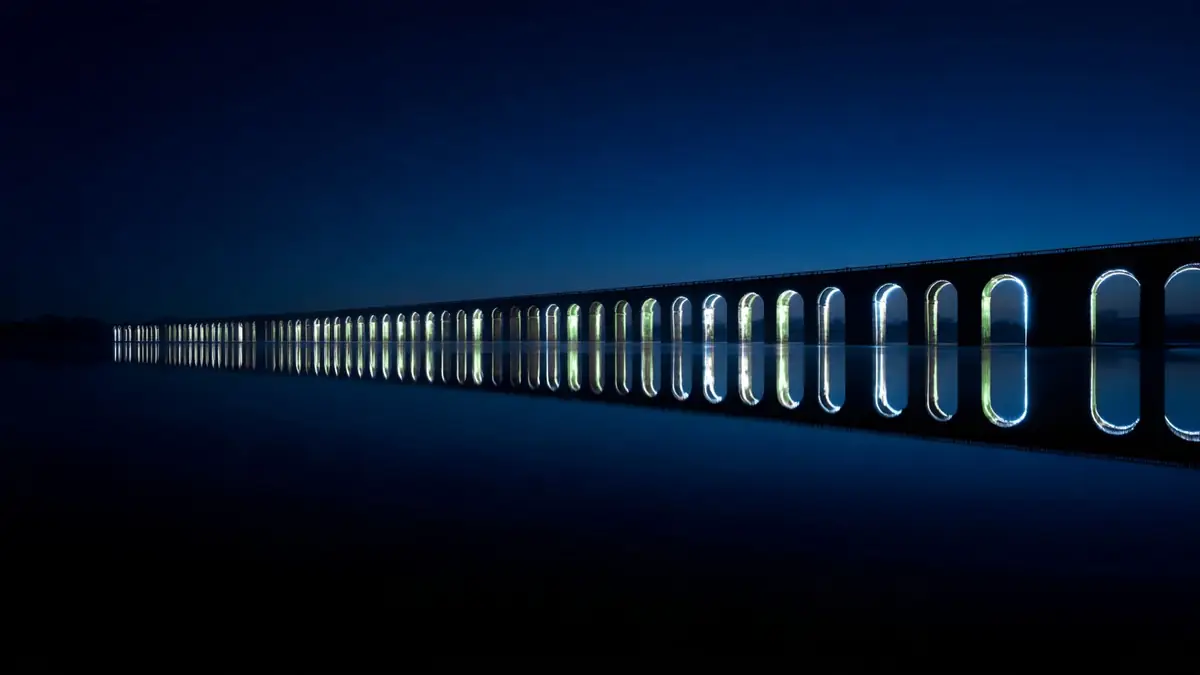 A long row of lit arches reflected in still dark water.