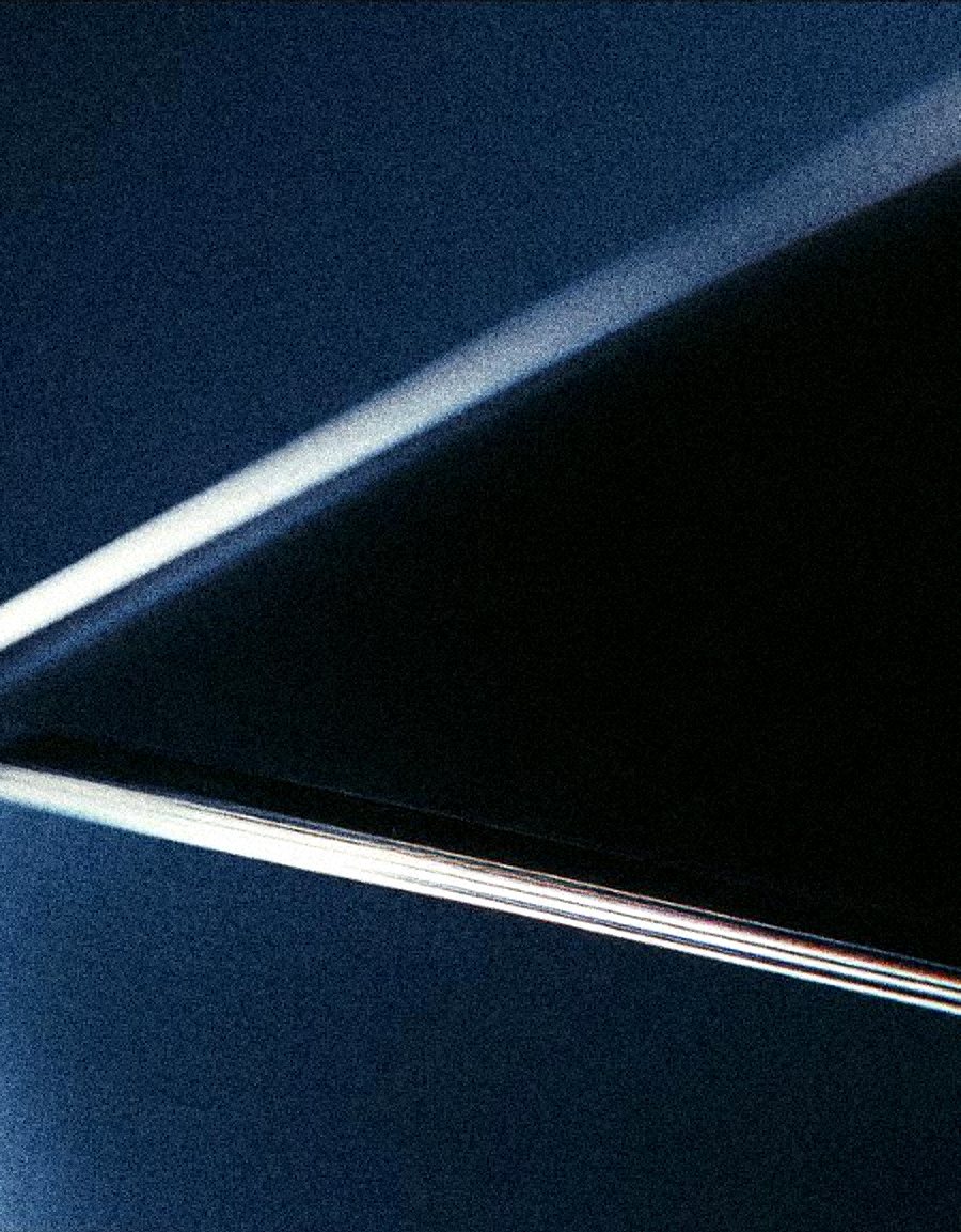 A black glass slab edge catching a hairline of white light and a spectrum